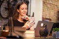 Happy young cheerful business woman smiling, sitting in the office, working from home, using laptop computer and mobile phone, Royalty Free Stock Photo