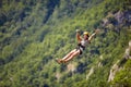 Happy young cheerful female tourist wearing casual clothes riding on zipline in forest. Zipline trip selective focus against