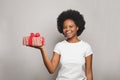 Happy young cheerful woman wearing white t-shirt smiling and holding red gift box against white studio wall banner background Royalty Free Stock Photo