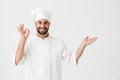 Happy young chef posing isolated over white wall background in uniform make okay gesture showing copyspace