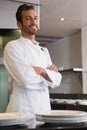 Happy young chef standing with arms crossed behind counter Royalty Free Stock Photo