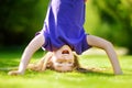 Happy young child playing head over heels on green grass in spring park Royalty Free Stock Photo