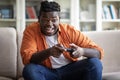 Happy young chubby black man playing video games at home Royalty Free Stock Photo