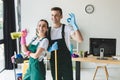 happy young cleaning company workers holding cleaning equipment and showing