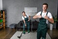 happy young cleaning company workers using vacuum cleaner and showing Royalty Free Stock Photo