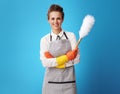 Happy young cleaning woman with dust cleaning brush on blue