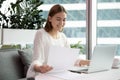 Happy young company employee holding documents, satisfied with report results.