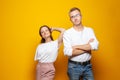 Happy young confedent couple standing against bright orange studio wall background Royalty Free Stock Photo