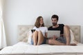 Happy young couple on bed online shopping. Happy smiling young couple in love at home, sitting on bed looking at laptop computer Royalty Free Stock Photo