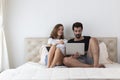 Happy young couple on bed online shopping. Happy smiling young couple in love at home, sitting on bed looking at laptop computer Royalty Free Stock Photo