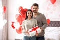 Happy young couple in bedroom decorated with heart balloons. Valentine`s day celebration