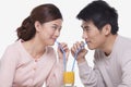 Happy young couple bonding and sharing a glass of orange juice, studio shot