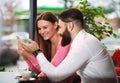 Happy young couple in cafe looking into a smart phone Royalty Free Stock Photo