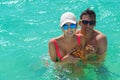 Happy young couple in the caribbean sea, they are holding a live starfish Royalty Free Stock Photo