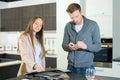 happy young couple choosing kitchen stove in hypermarket