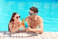 Happy young couple with cocktails in  pool Royalty Free Stock Photo