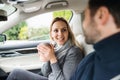 Happy young couple with coffee sitting in car, talking. Royalty Free Stock Photo