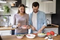 Happy young couple cooking salad together, preparing dinner at home Royalty Free Stock Photo