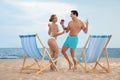 Happy young couple dancing near deck chairs at beach Royalty Free Stock Photo