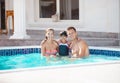 Happy young couple and daughter in swimming pool near luxury villa. Royalty Free Stock Photo