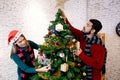 Happy young couple decorating and preparation ornament on Christmas tree together with enjoy at home. Royalty Free Stock Photo