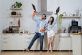 Happy young couple doing home chores, singing and having fun. Funny woman singing songs and dancing while cleaning kitchen at home Royalty Free Stock Photo