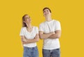 Happy young couple standing isolated on yellow background, looking up and smiling Royalty Free Stock Photo