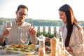 Happy young couple eating fish dinner in riverside restaurant