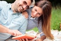 Happy young couple enjoying day in nature, reading a book and lying on a picnic blanket Royalty Free Stock Photo