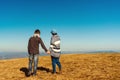 Happy young couple enjoying nature at mountain peak. Loving couple holding hands over blue sky background. Love, freedom, dream