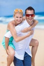 Happy young couple enjoying a solitary beach backriding