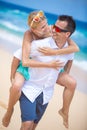 Happy young couple enjoying a solitary beach backriding