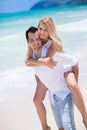 Happy young couple enjoying a solitary beach backriding