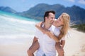 Happy young couple enjoying a solitary beach backriding