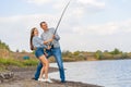 Happy young couple fishing by lakeside