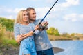 Happy young couple fishing by lakeside a