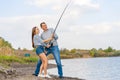 Happy young couple fishing by lakeside