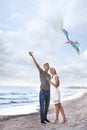 Happy young couple flying kite near sea Royalty Free Stock Photo