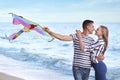 Happy young couple flying kite near sea Royalty Free Stock Photo