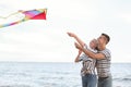 Happy young couple flying kite near sea Royalty Free Stock Photo