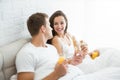 Happy young couple handsome man and beautiful woman having breakfast in bed eating croissant and drinking orange juice Royalty Free Stock Photo