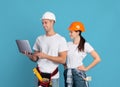 Happy young couple in hardhats using laptop, ordering materials for repair apartment Royalty Free Stock Photo