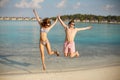 Happy young couple have fun and relax on the beach. Man and woman jump holding hands and smiling. Bungalows of spa Royalty Free Stock Photo