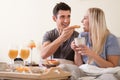 Happy young couple having breakfast in bed Royalty Free Stock Photo