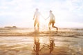 Happy young couple having fun on the beach at sunset, water splash