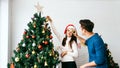 Happy young couple having fun decorating various baubles on the Christmas tree in the living room at home. Enjoying. Royalty Free Stock Photo