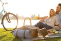 Happy young couple having picnic near lake, focus on basket with blanket and hat Royalty Free Stock Photo