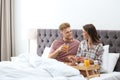 Happy young couple having romantic breakfast in bed Royalty Free Stock Photo