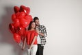 Happy young couple with heart shaped balloons on background, space for text. Valentine`s day celebration