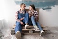 Happy young couple holding cup of tea and resting from home repair. Repair, interior design, renovation and home Royalty Free Stock Photo